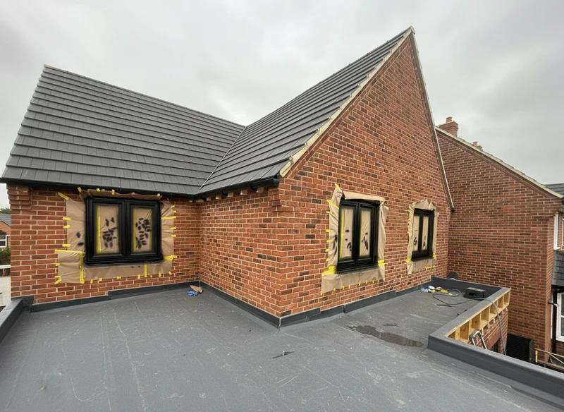 Black window frames with professional masking on brick house - window spraying